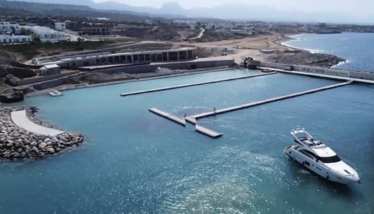 Neue Marina in Esentepe mit Stegen, Wellenbrecher und einer Motorjacht