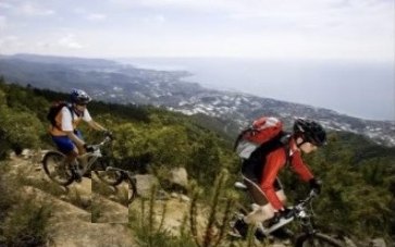 Zwei Mountainbiker auf einem Trail mit Blick auf Küste und Meer