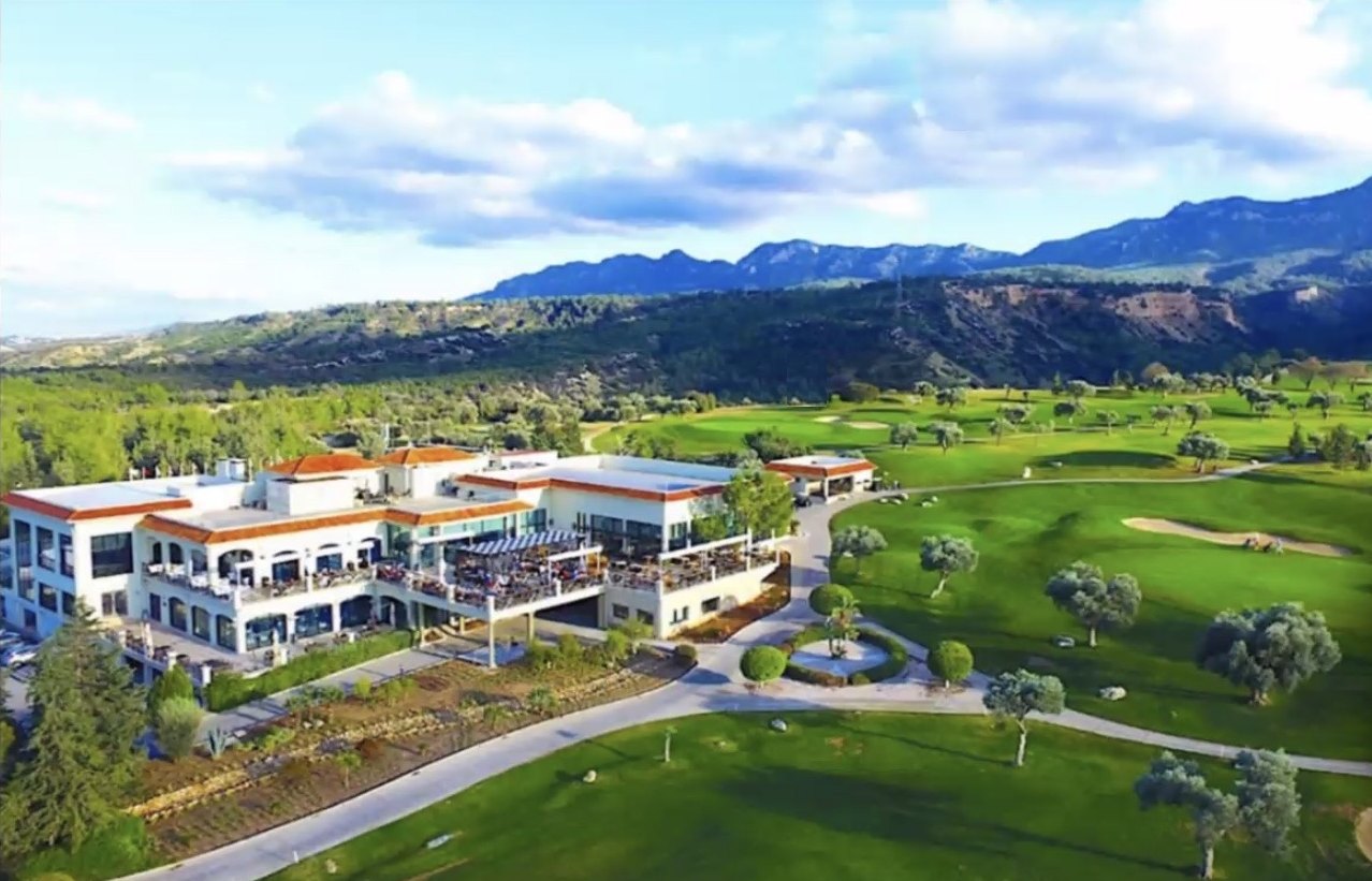 Golfresort mit Clubhaus, Olivenbäumen und dem Kyrenia-Gebirge im Hintergrund