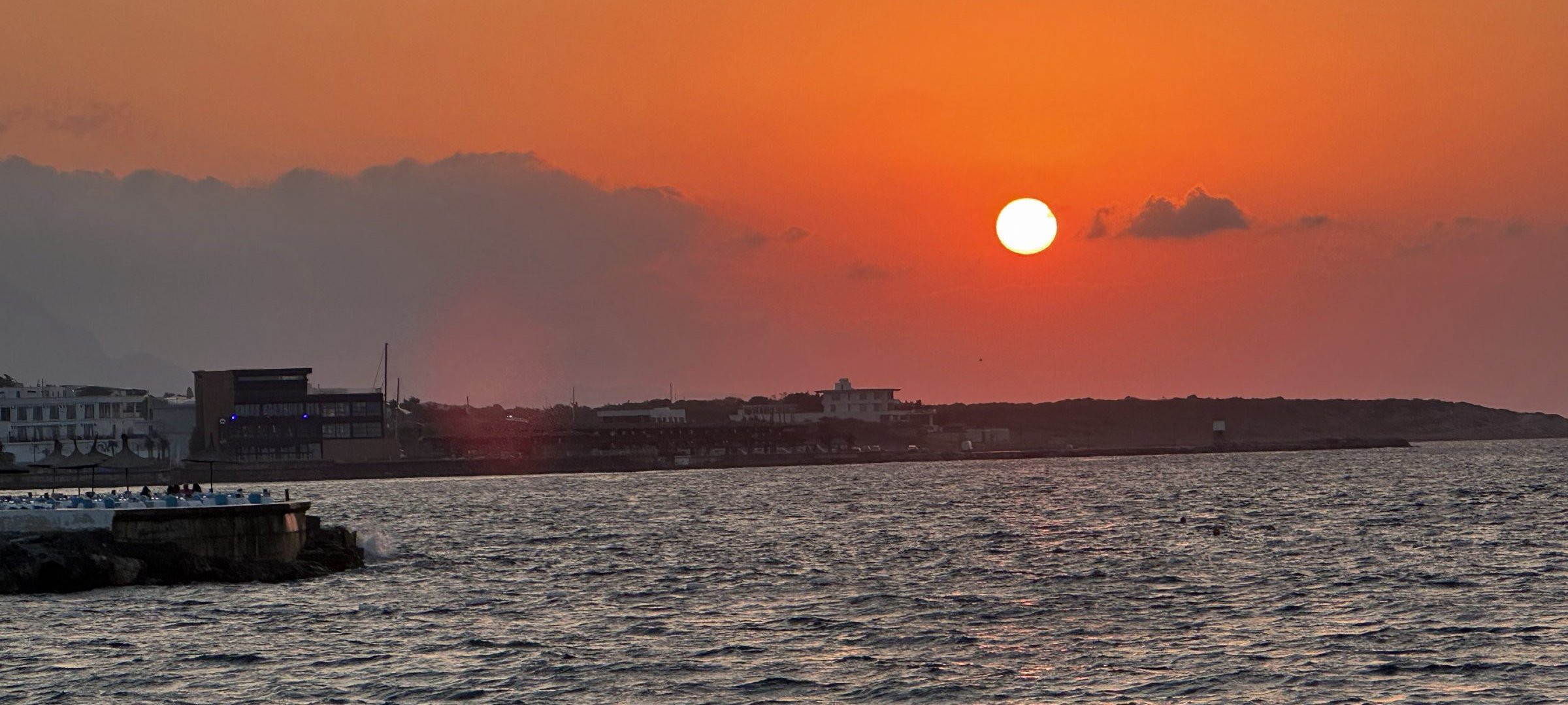 Sonnenuntergang über dem Meer an der Nordküste mit Hafenmole und Küstenlinie